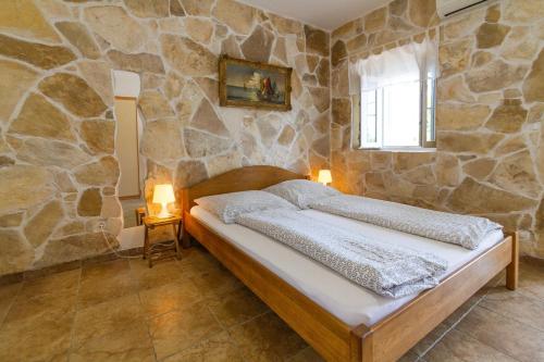 a bedroom with a bed in a stone wall at Apartments Kaktus Orebic in Orebić