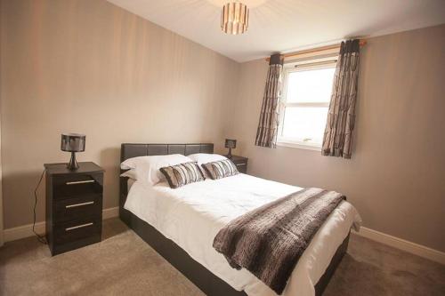 a bedroom with a bed and a lamp and a window at City Centre Executive 2 Bed Apartment with WiFi & Parking in Aberdeen