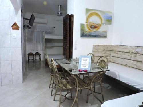 a dining room with a glass table and chairs at Condomínio Vilalba in Ubatuba