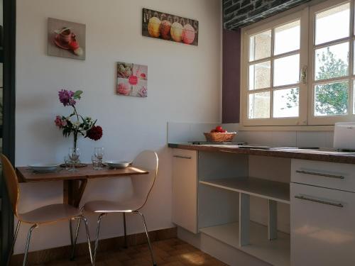 une cuisine avec une table, deux chaises et un comptoir dans l'établissement Gîte 2 pers proche plage avec jardin, à Clohars-Carnoët