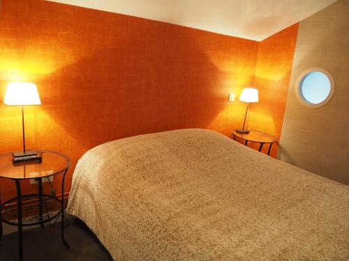 a bedroom with a bed and two tables with lamps at Hôtel La Villa Lorraine in Toul