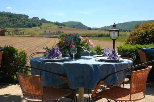 uma mesa com uma toalha de mesa e cadeiras azuis e um campo em Le Relais des 5 Chateaux em Vézac