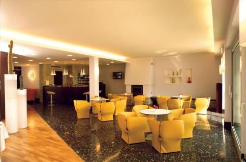 a restaurant with yellow chairs and tables and a bar at Hotel Bel Sit in Meina
