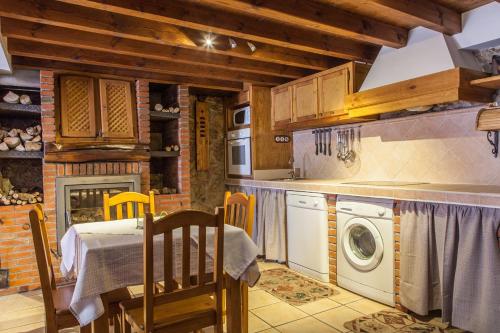 a kitchen with a table and a washing machine at Apartamentos Rurales El Tio Pablo Picos de Europa Tresviso in Tresviso