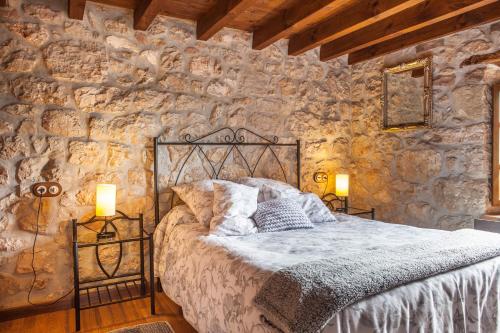 a bedroom with a bed in a stone wall at Apartamentos Rurales El Tio Pablo Picos de Europa Tresviso in Tresviso