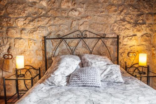 a bed in a stone wall with two lamps on it at Apartamentos Rurales El Tio Pablo Picos de Europa Tresviso in Tresviso