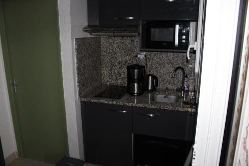 une petite cuisine avec un évier et un micro-ondes dans l'établissement LE CLUB - APPARTEMENT T3 Centre ville, à La Grande Motte