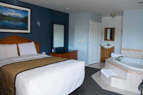 a bedroom with a large bed and a bath tub at At 9 Motel in Howell