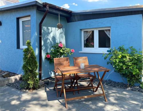 einen Holztisch und zwei Stühle vor einem blauen Haus in der Unterkunft Gaude Tiet in Insel Poel