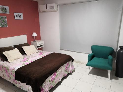 a bedroom with a bed and a green chair at Duplex a pasitos del centro contactar número primer foto in Posadas