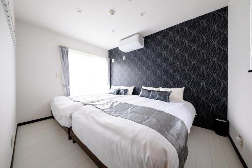 een slaapkamer met een groot bed met een muur met zwarte accenten bij Minamitsuru-gun - House - Vacation STAY 82405 in Fujikawaguchiko