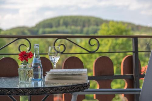 a table with a glass of wine and a flower on it at Landhaus Heimisch Bed & Breakfast in Geisfeld