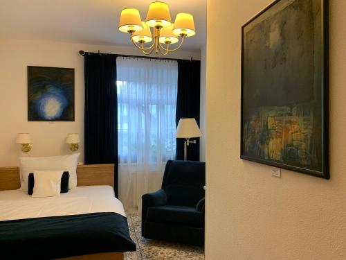 a bedroom with a bed and a chair and a window at Antik Hotel Sofia in Litomyšl