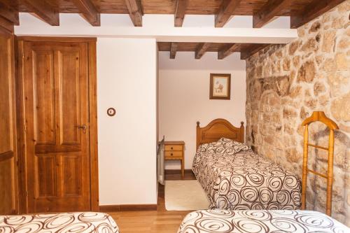a bedroom with a bed and a stone wall at Apartamentos Rurales El Tio Pablo Picos de Europa Tresviso in Tresviso