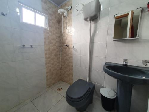 uma casa de banho com um WC azul e um lavatório. em 01 - Casa Praia da Pinheira pousada em Palhoça