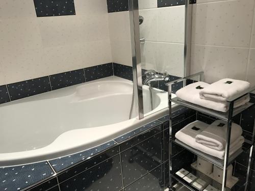 a bathroom with a tub and a sink and towels at Antik Hotel Sofia in Litomyšl