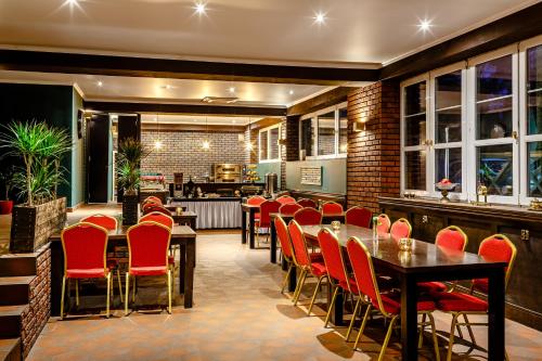 a restaurant with red chairs and tables and a bar at Villa Malva in Łomianki