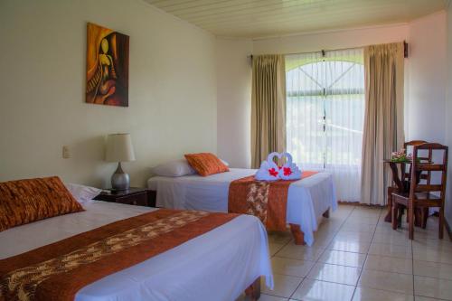 una camera d'albergo con due letti e una finestra di Hotel Vista del Cerro a Fortuna