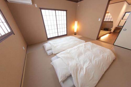 dwa łóżka w pokoju z dwoma oknami w obiekcie SyukuyaYokohama Main Building 1F - Vacation STAY 82573 w mieście Kitagatamachi