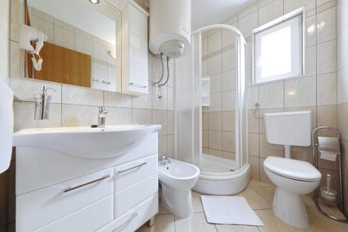 biała łazienka z umywalką i toaletą w obiekcie Villa Rajna w mieście Starigrad-Paklenica