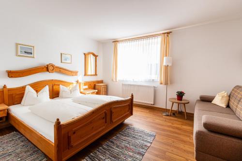a bedroom with a large wooden bed and a couch at Hotel Gasthof Neuwirt in Holzkirchen