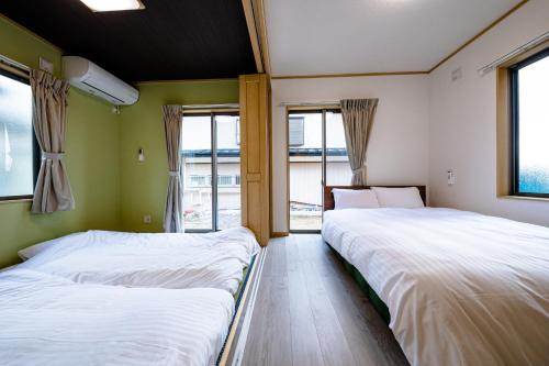 dwa łóżka w pokoju z oknami w obiekcie Minamitsuru-gun - House - Vacation STAY 82837 w mieście Fujikawaguchiko