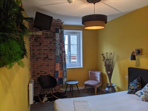a bedroom with a bed and a tv on a brick wall at L'Aiguille Creuse in Étretat