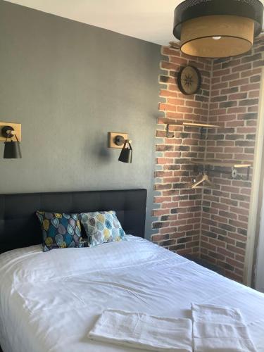 a bedroom with a bed and a brick wall at L'Aiguille Creuse in Étretat