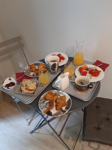 Una mesa cubierta con platos de desayuno y jugo de naranja. en La Villa Claudia Jardin et Spa, en Pennautier