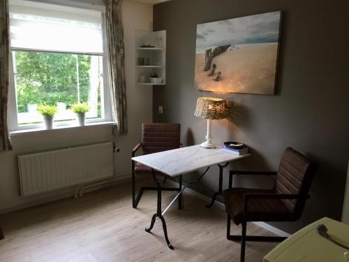 um quarto com uma mesa e duas cadeiras e uma janela em de Duinroos em Oostkapelle