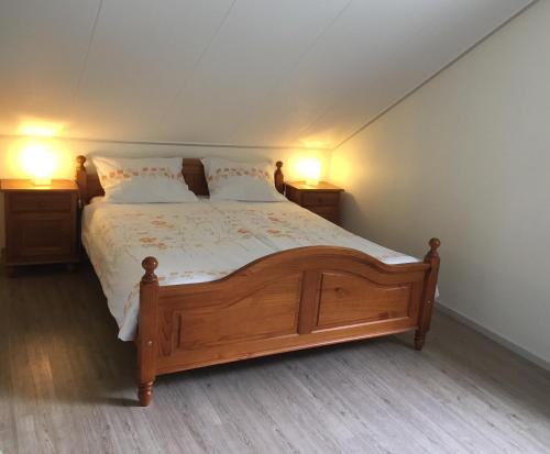 een slaapkamer met een groot houten bed met 2 lampen bij de Duinroos in Oostkapelle