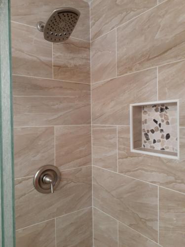 a shower with a beige tiled wall at Atlantic Breeze Motel & Apartments in Ocean City