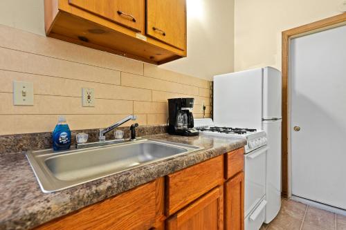a kitchen with a sink and a white refrigerator at Harney Camp Cabins in Hill City
