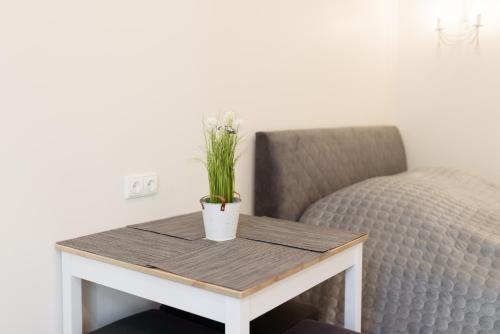 a table with flowers on it next to a bed at Prie Ąžuolo in Juodkrantė