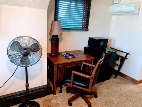 a room with a desk with a fan and a chair at Iowa House Historic Inn in Ames