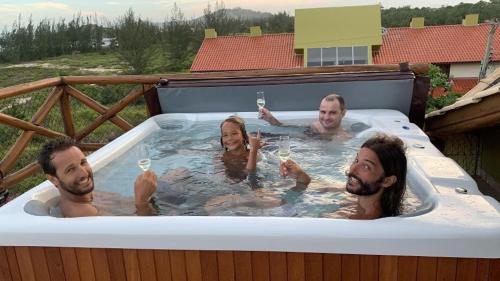 a group of people in a hot tub with wine glasses at Pousada Pé na Areia in Garopaba