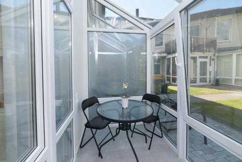 a glass balcony with a table and two chairs at Prie Ąžuolo in Juodkrantė