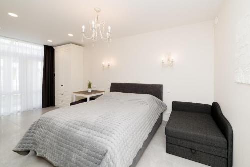 a white bedroom with a bed and a chair at Prie Ąžuolo in Juodkrantė