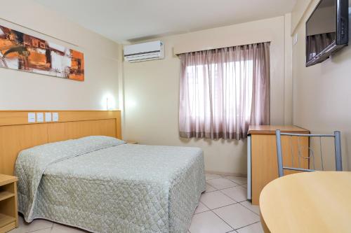 1 dormitorio con cama, mesa y ventana en Hotel Express São Leopoldo, en São Leopoldo
