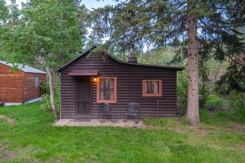 a small cabin with two chairs in a yard at Harney Camp Cabins in Hill City