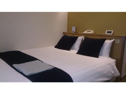 Schlafzimmer mit einem Bett mit weißer Bettwäsche und schwarzen Kissen in der Unterkunft Hotel St Palace Kurayoshi - Vacation STAY 82276 in Kurayoshi