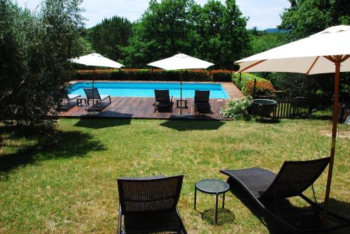 西恩納的住宿－波爾格風笛度假屋，一组椅子和遮阳伞,位于游泳池旁