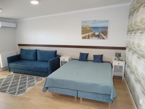 - une chambre avec un lit et un canapé bleu dans l'établissement Willa Morska, à Mielenko