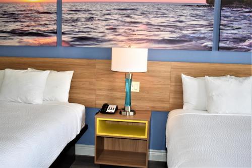 a hotel room with two beds and a table with a lamp at Days Inn & Suites by Wyndham Downtown/University of Houston in Houston