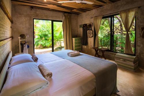 a bedroom with a large white bed with windows at Suites Tulum in Tulum