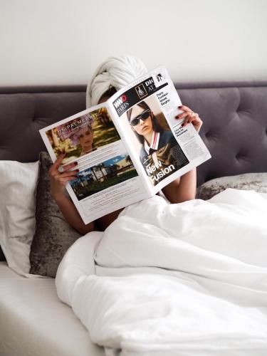 a woman laying in bed reading a magazine at Apartmány Mia Valtice in Valtice