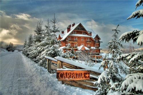a large building covered in snow with a fence at Hotel Carpatia Bieszczadzki Gościniec in Wetlina