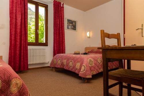 - une chambre avec un lit, un bureau et une fenêtre dans l'établissement Hôtel de la Mairie, à LʼArgentière-la-Bessée