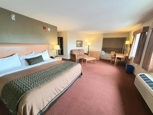 a hotel room with a large bed and a chair at AmeriVu Inn and Suites - Waconia in Waconia