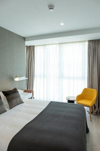 a bedroom with a large bed and a yellow chair at CONCHEIROS 5 APARTAMENTOS TURISTICOS in Santiago de Compostela